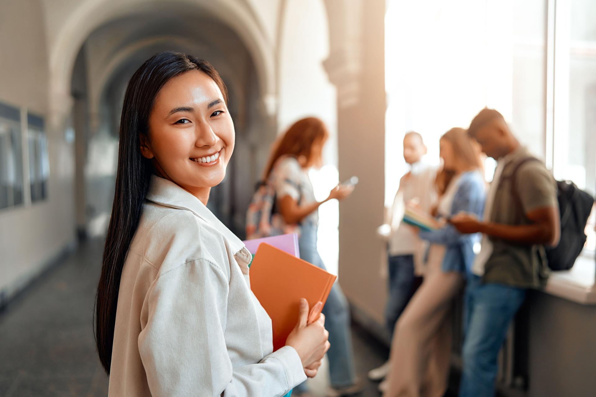 Students, including a cheerful teenager, study happily in the university hallway