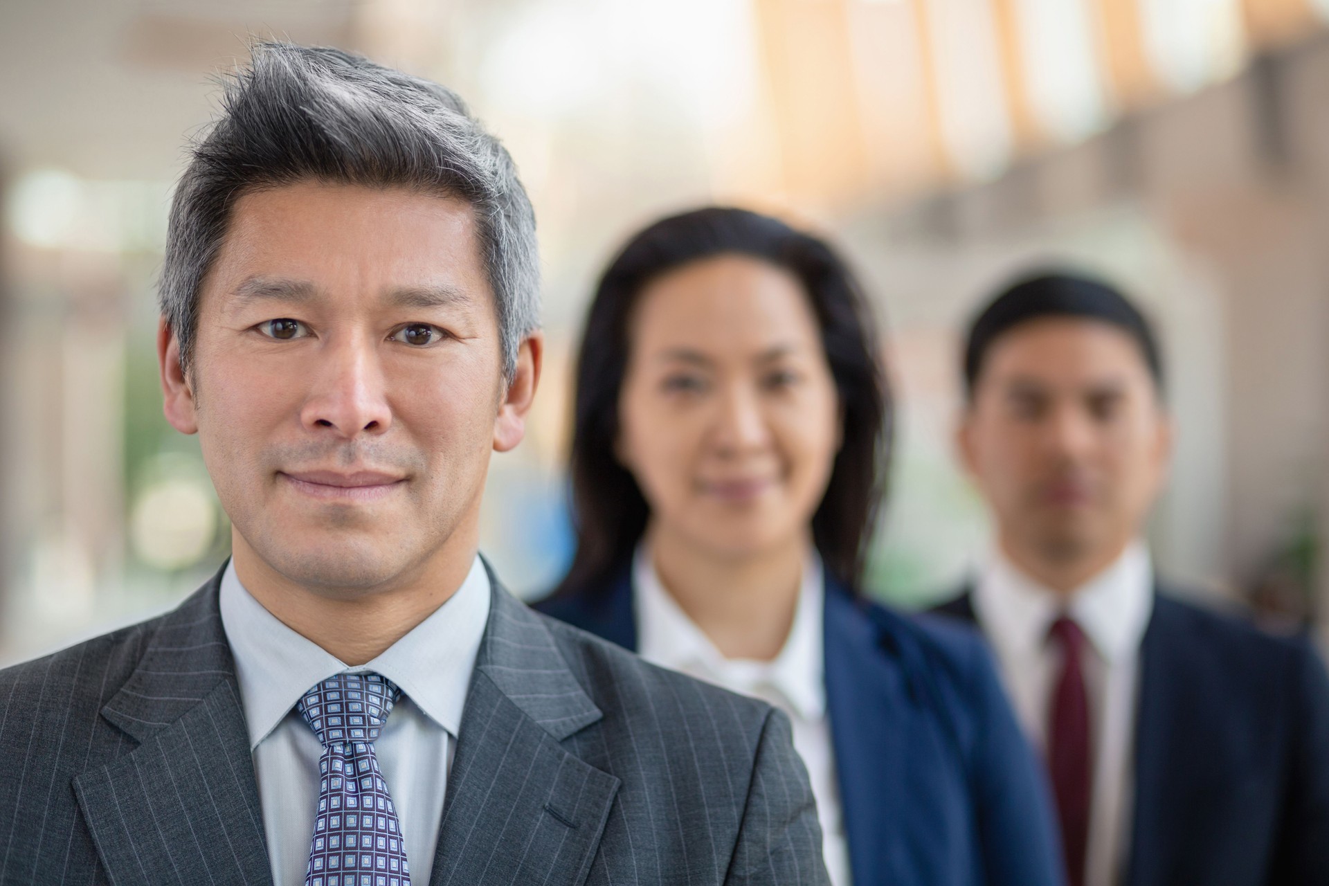 Portrait of mature Chinese businessman with multiracial colleagues in office in a row