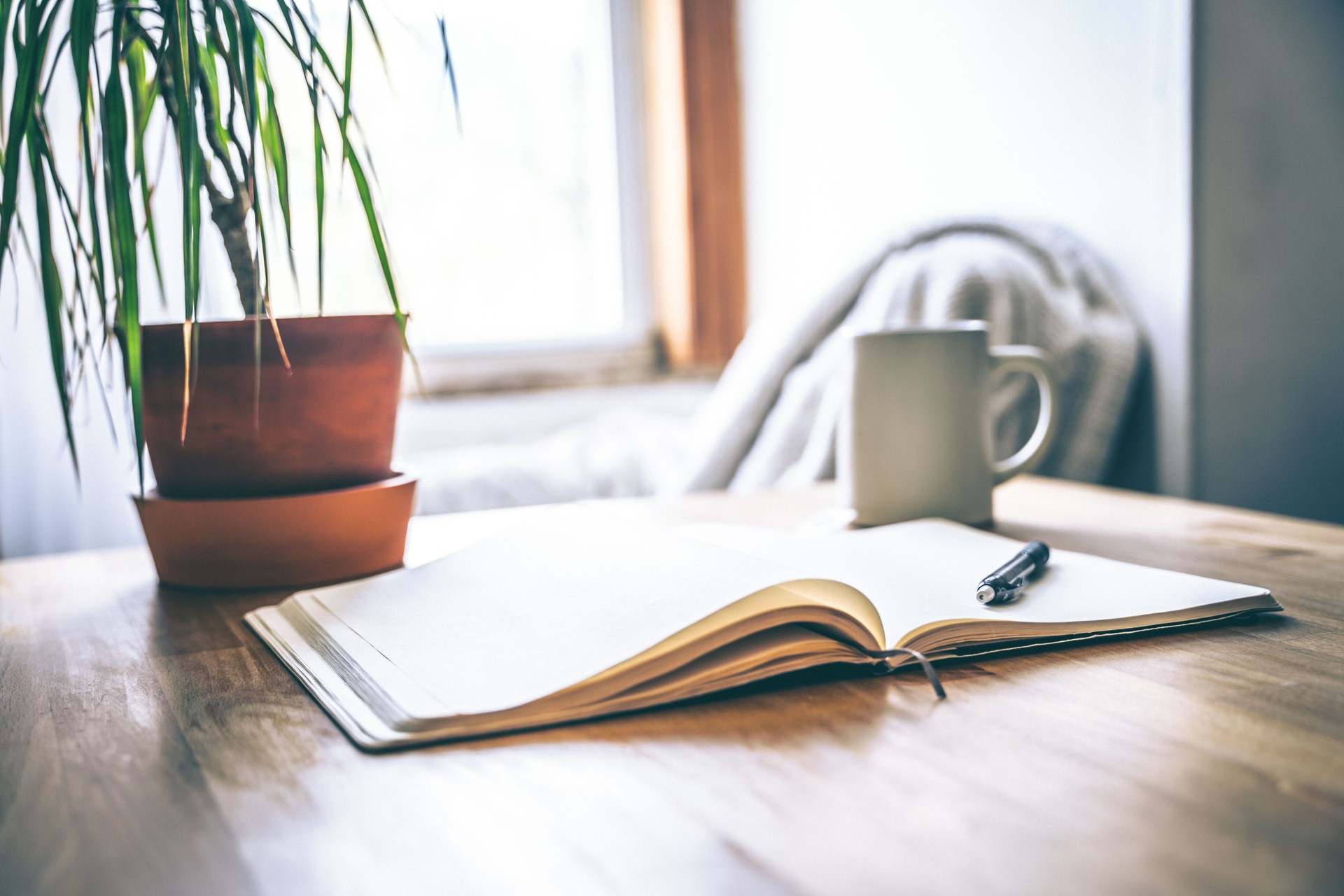 An open journal and pen on a table with a cup of tea for a mental health break.